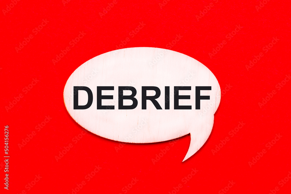 On a bright red background, a light wooden curly card with the text DEBRIEF