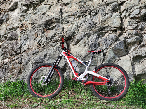 Full suspension downhill bicycle at rocky stone wall background © lilkin