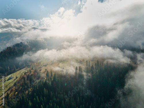 Aerial view of sea of fog floating rolling over mountain valley hills islands at sunrise, dark forest foreground. cloudy woods in mountains.