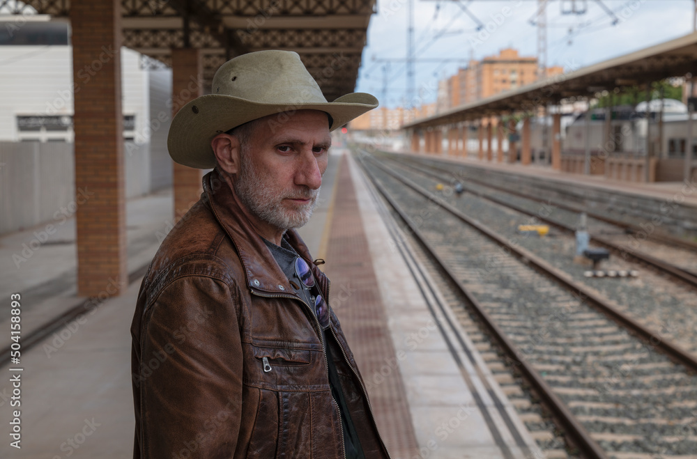 Portrait of adult man on cowboy hat waiting in train station. Almeria, Spain