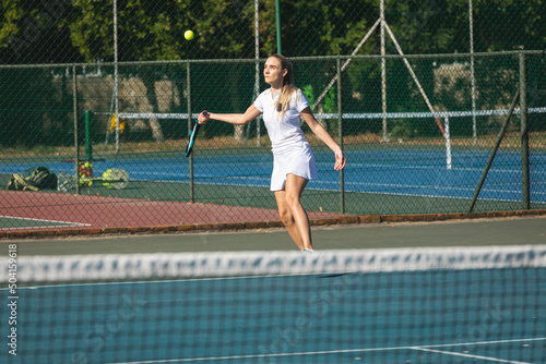 Caucasian young female tennis player playing at court on sunny day