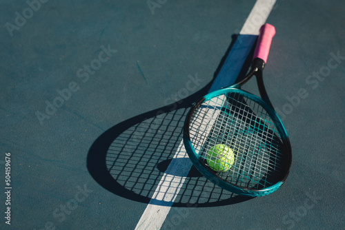 High angle view of tennis racket and ball with shadow by line on blue court during sunny day