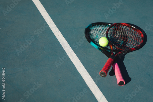 High angle view of rackets with ball by line on blue court during sunny day