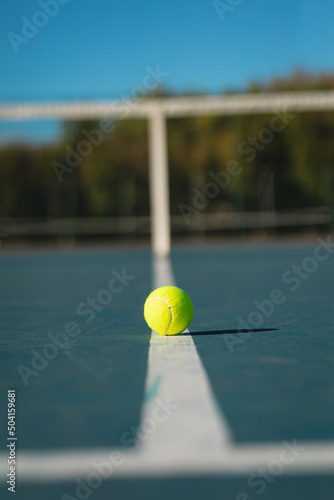 Surface level view of green ball on white line at empty court during sunny day