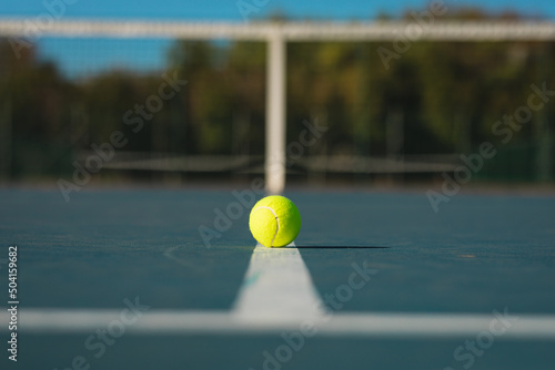 Green ball on white line at empty court during sunny day