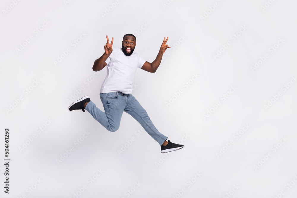 Fototapeta premium Photo of pretty cute guy dressed casual t-shirt jumping high running v-sign empty space isolated white color background