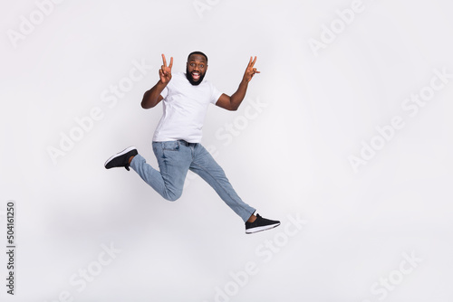 Photo of pretty cute guy dressed casual t-shirt jumping high running v-sign empty space isolated white color background