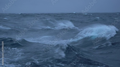 Storm. High waves. White foam on wind. Side view low on water. Wind breaks waves. Splashes