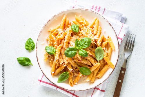 Pasta with tomato sauce, basil and parmesan on white table. Penne pasta with tomato sauce alla arrabbiata. Top view with copy space.