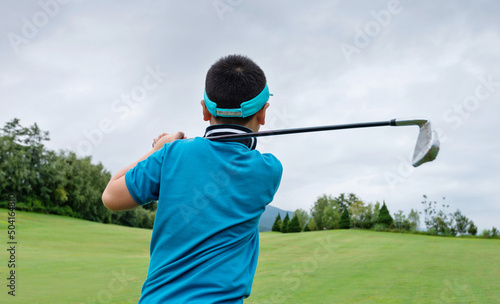Little boy playing golf on a field