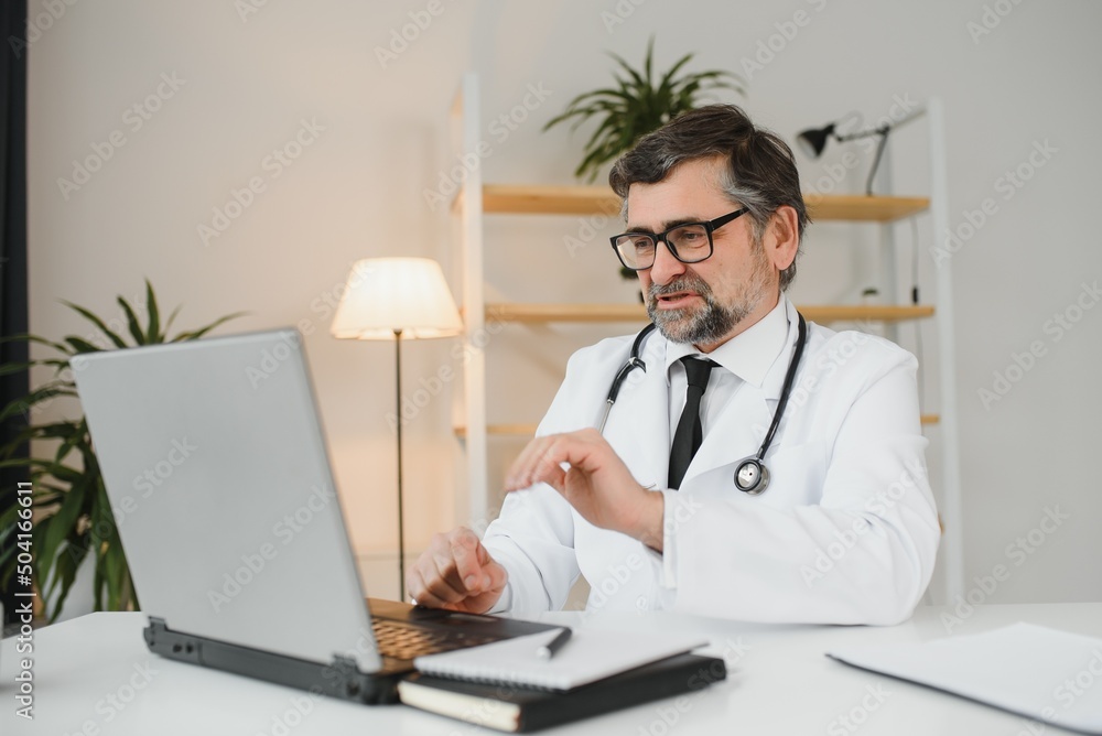 Remote medical consultation. A male doctor consults a woman has a video call conference computer monitor sitting in a clinic office Remote medical consultation. A male doctor consults a woman has a video call conference computer monitor sitting in a clinic office