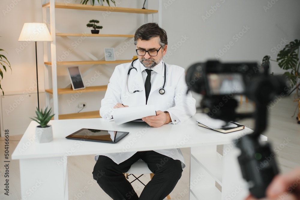 Handsome male doctor recording video for medical blog.