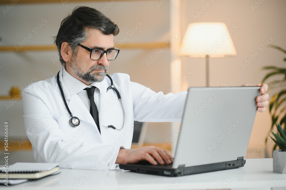 Portrait of a serious doctor using laptop in medical office Portrait of a serious doctor using laptop in medical office