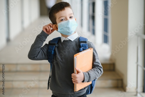 Little schoolboy wearing mask during corona virus and flu outbreak. llness protection for kids. Mask for coronavirus prevention. School kid coughing. Little boy breathes through mask, going to school. photo