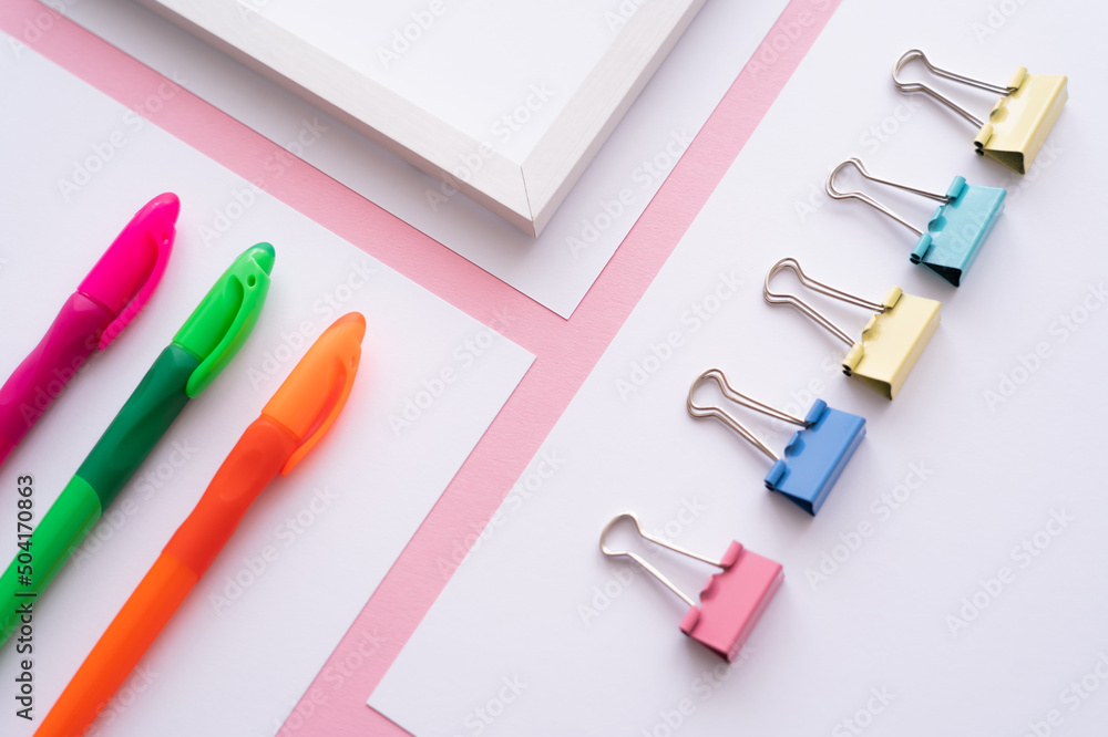 high angle view of colorful stationery on white papers on pink. high angle view of colorful stationery on white papers on pink.