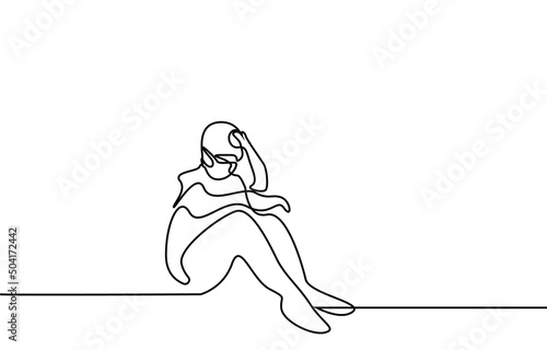 A doctor in surgical clothes is sitting on the floor sad and tired.