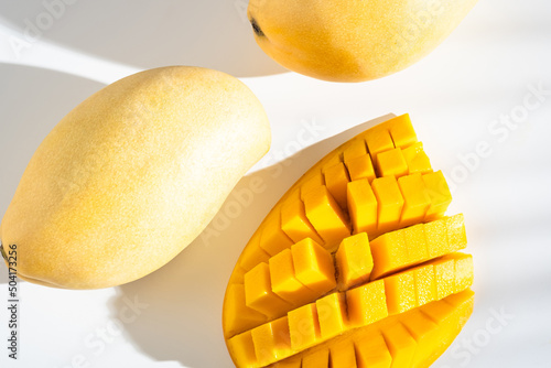 Juicy ripe yellow Thai mango on a white background. Hard light and shadow from a palm tree.