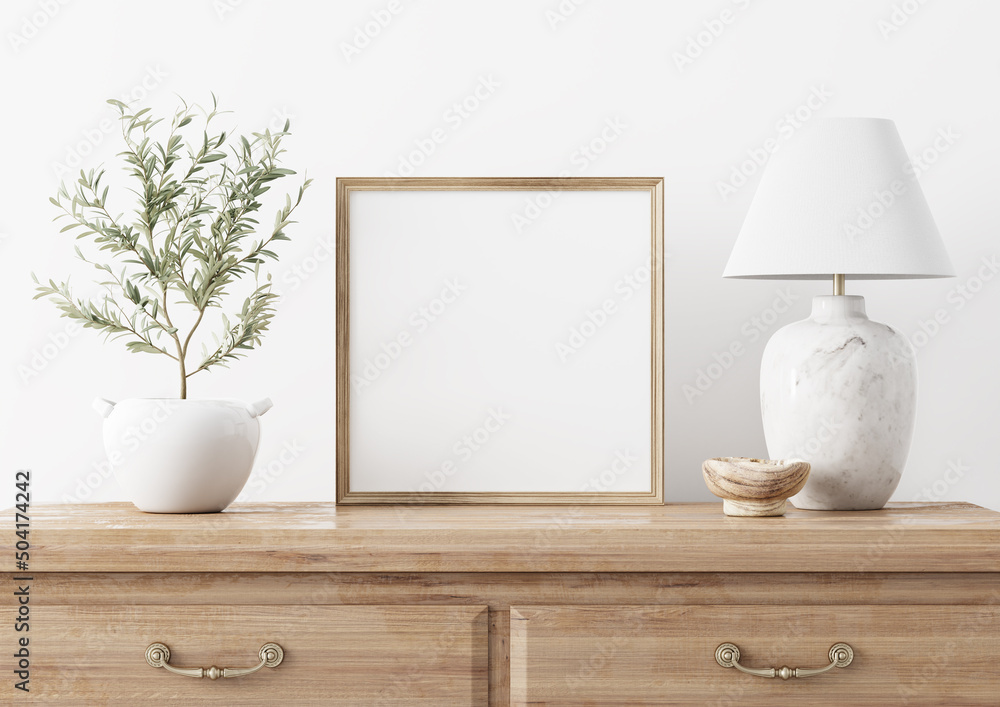 Square wooden frame mockup in traditional living room interior with classic chest of drawers, marble lamp and small olive tree on white wall background. Illustration, 3d rendering Square wooden frame mockup in traditional living room interior with classic chest of drawers, marble lamp and small olive tree on white wall background. Illustration, 3d rendering