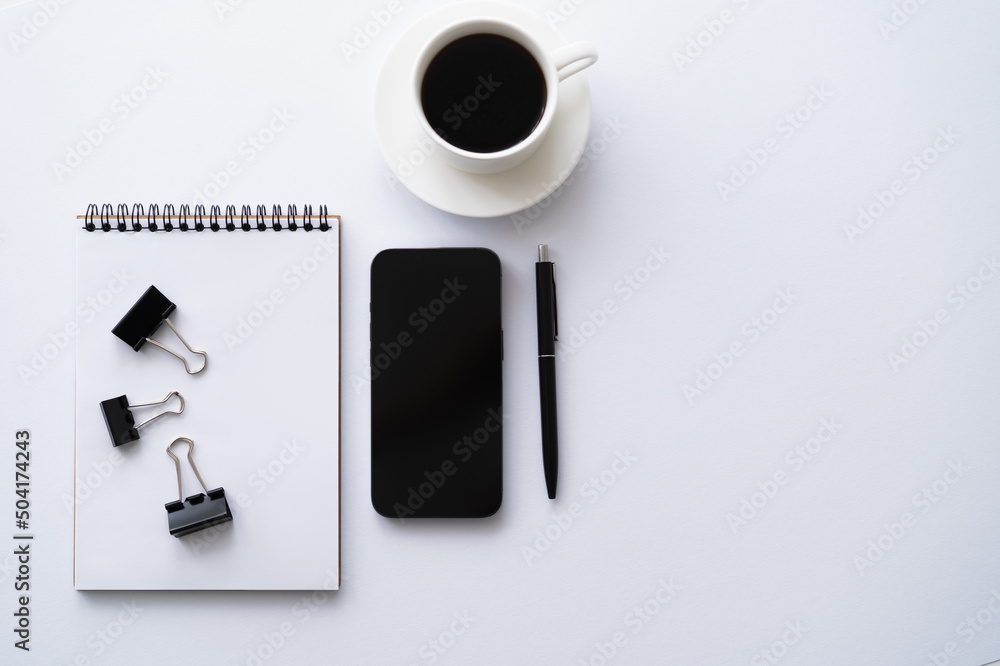 top view of cellphone with blank screen near cup of coffee and stationery on white. top view of cellphone with blank screen near cup of coffee and stationery on white.