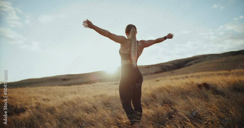 Beautiful young fitness woman in golden field with windmills in the distance at sunset, health, wellness and sustainability concept Beautiful young fitness woman in golden field with windmills in the distance at sunset, health, wellness and sustainability concept