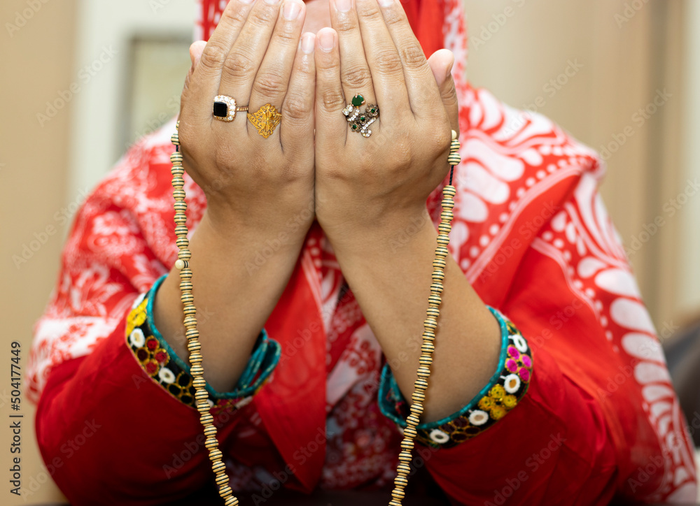 Young Muslim Woman with Colour full beads praying on Wood background With Red Cloth, closeup young Muslim woman making dua.