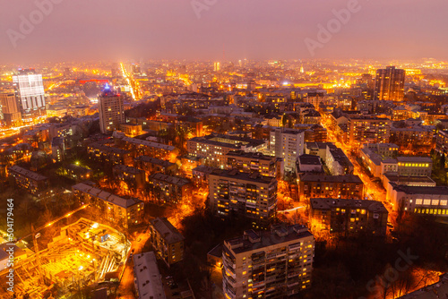 Ukraine, Kyiv – March 12, 2016: Aerial panoramic view on central part of Kyiv city from a roof of a high-rise building. Night life in a big city. Foggy and rainy weather. © Bohdan