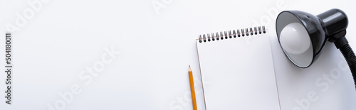 top view of blank notebook near pencil and lamp on white, banner.