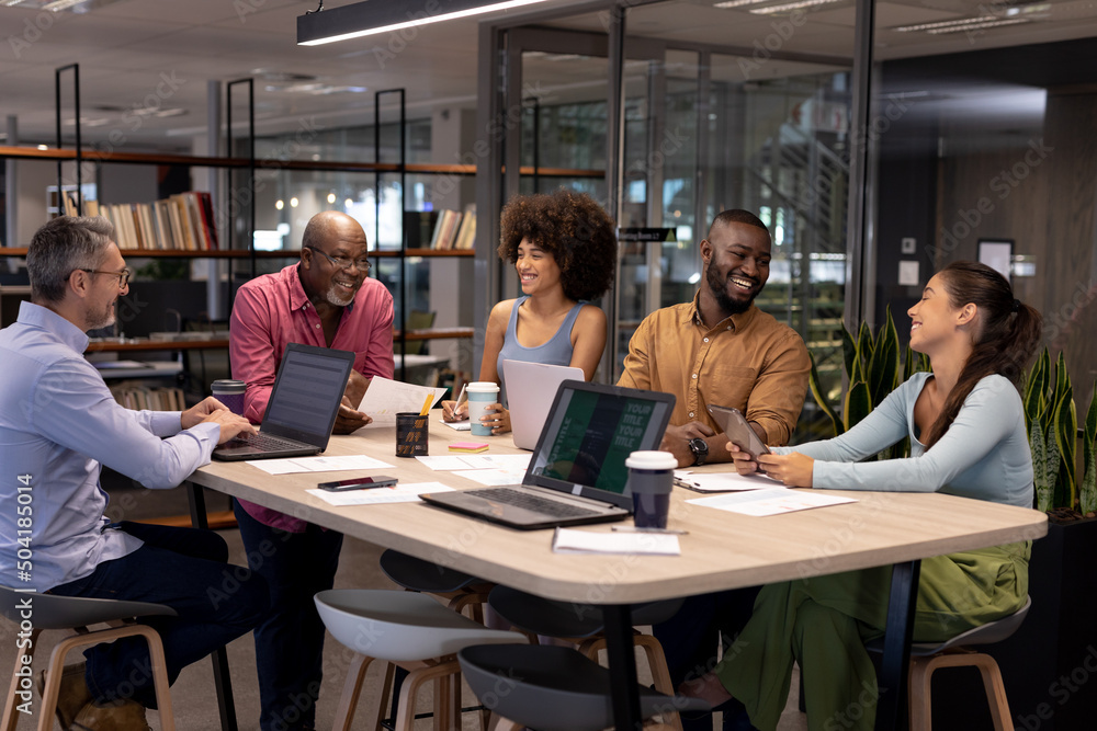 Smiling multiracial colleagues discussing during meeting at modern workplace Smiling multiracial colleagues discussing during meeting at modern workplace