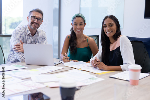 Portrait of happy multiracial businessman and businesswomen sitting in boardroom during meeting
