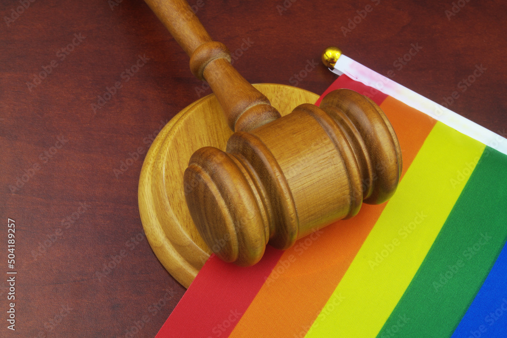 Wooden judge gavel with LGBT pride flag close-up.	