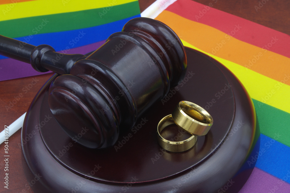 LGBT marriage equality and laws concept. Wedding rings, wooden gavel and LGBT flags.	