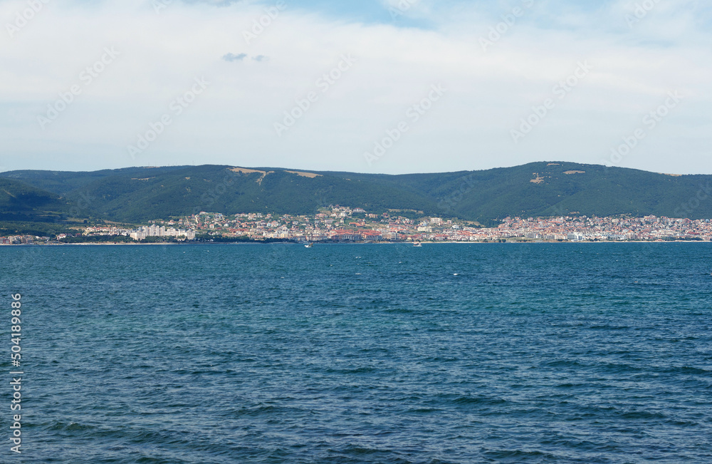 Black sea, blue water, hotels of resort area where people rest are visible in distance, against the background of hills