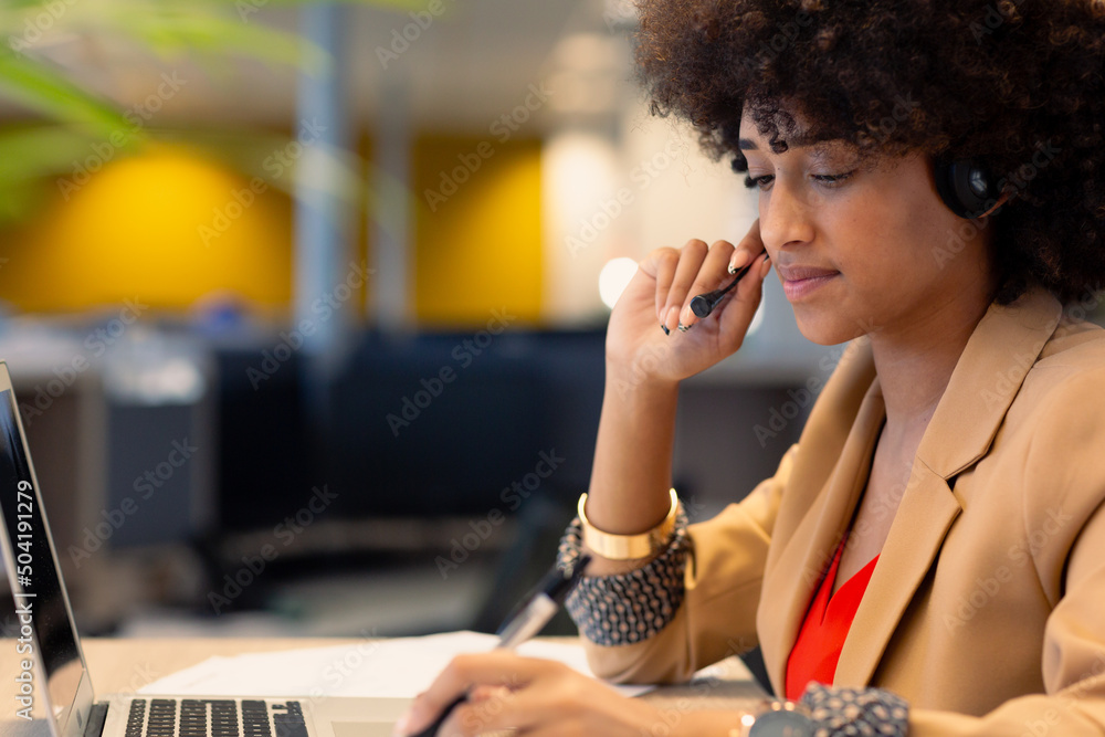 Afro young african american businesswoman with headset using laptop at modern workplace