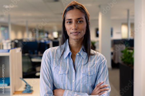 Portrait of beautiful young female african american advisor with arms crossed at modern workplace