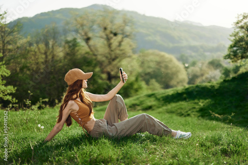 Blogger with phone working in park on grass by tree, freelancer lifestyle photo