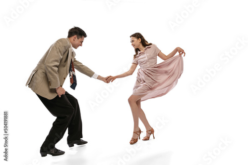 Fototapeta Naklejka Na Ścianę i Meble -  Young man and woman in vintage retro style outfits dancing social dance isolated on white background. Timeless traditions, 1960s american fashion style and art