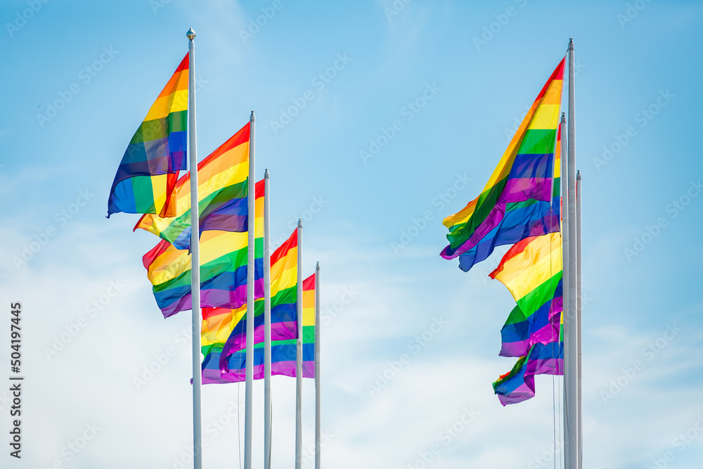 Rainbow flag fluttering against blue sky, Pride LGBT community symbol Rainbow flag fluttering against blue sky, Pride LGBT community symbol