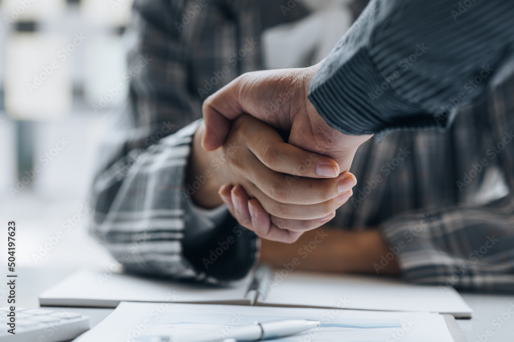 Obraz premium Close-up two business men holding hands, Two businessmen are agreeing on business together and shaking hands after a successful negotiation. Handshaking is a Western greeting or congratulation.