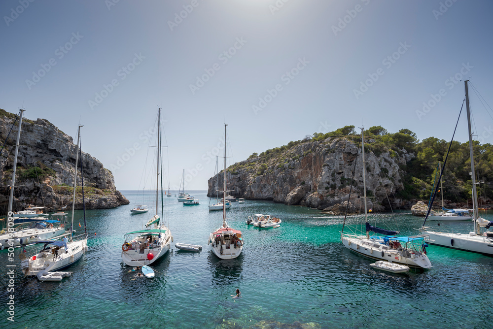 Sailing boats anchored in Cales Coves, a famous cove in the municipality of Alaior, Menorca, Spain