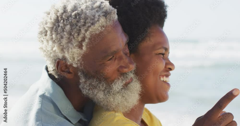 Happy african american couple sitting and embracing on sunny beach Happy african american couple sitting and embracing on sunny beach