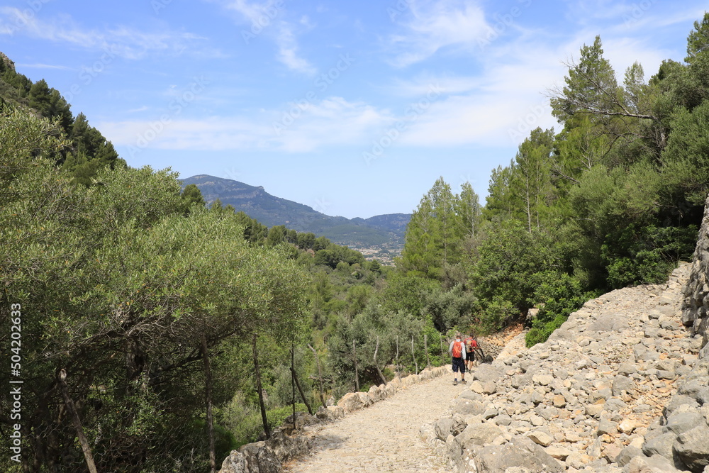 Gente practicando senderismo por un camino empedrado de las montañas de la Serra de Tramuntana de Mallorca. Gente practicando senderismo por un camino empedrado de las montañas de la Serra de Tramuntana de Mallorca.