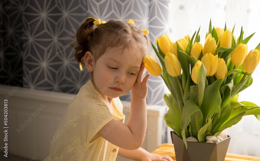 A sad girl with a bouquet of yellow tulips looks to the side. The holiday does not bring happiness to the child, it is mournful. Congratulations on the spring holidays . child with yellow tulips A sad girl with a bouquet of yellow tulips looks to the side. The holiday does not bring happiness to the child, it is mournful. Congratulations on the spring holidays . child with yellow tulips