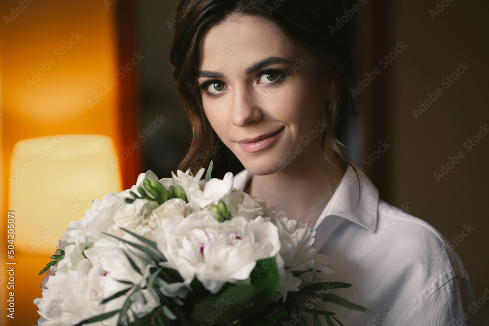 Portrait of a beautiful delicate bride in a white shirt with a wedding bouquet