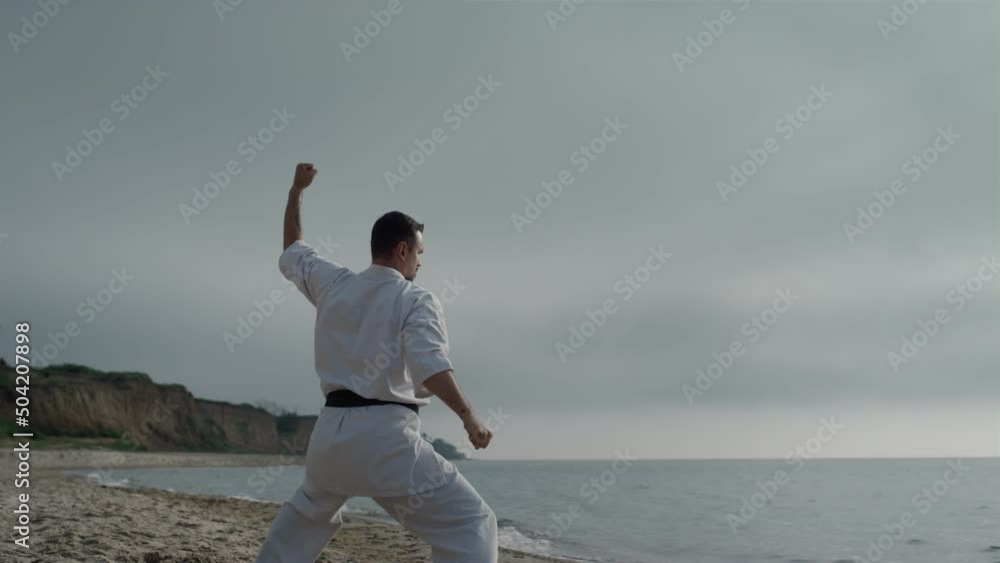 Karate fighter training strength on beach. Man standing in fighting position. Karate fighter training strength on beach. Man standing in fighting position.