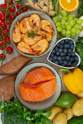 shrimps, salmon fillet and fresh vegetables and fruits arranged around it