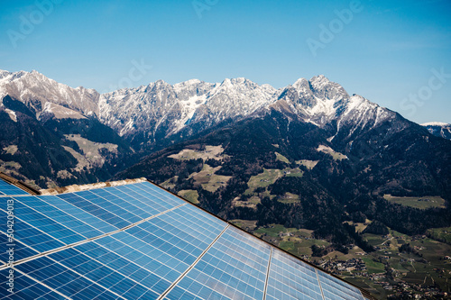 Dach mit Photovoltaik bei Sonnenschein, hoch in den Bergen. Solaranlage, im Hintergrund schneebedeckte Berge in Südtirol