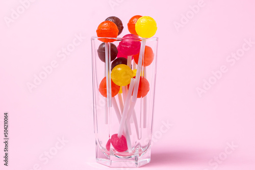 Lollipops in a glass on a pink background. Various fruit candies. sweet treat