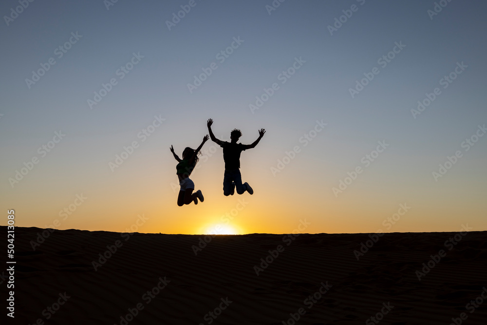 Silueta de jóvenes saltando alegres al atardecer