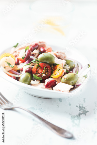 Salad with tuna, green olives and cherry tomatoes. Bright wooden background. Close up.