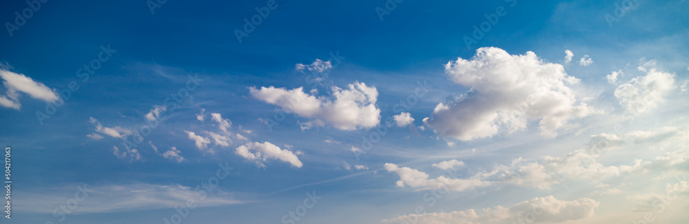 Beautiful blue sky with stunning volumetric clouds illuminated by the sun. Banner size, copyspace